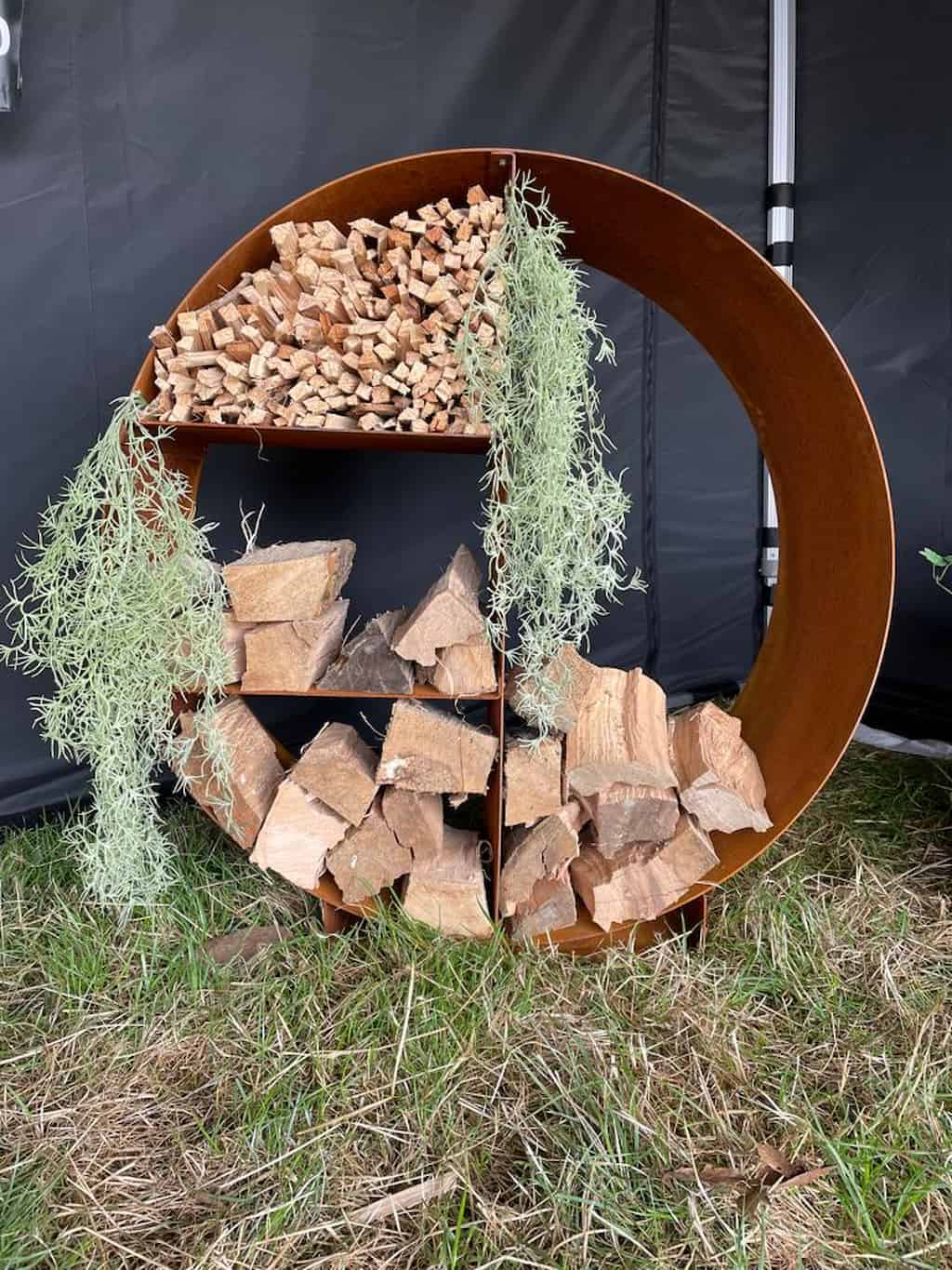 circular corten log store split in to 4 sections with kindling and logs inside