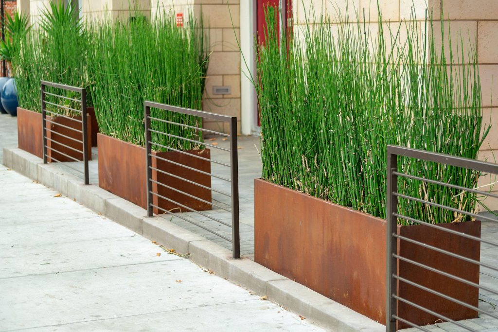 row of 3 corten steel planters on pavement