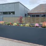 Large grey 7024 steel trough planter with plants inside in a patio garden with a house in the background